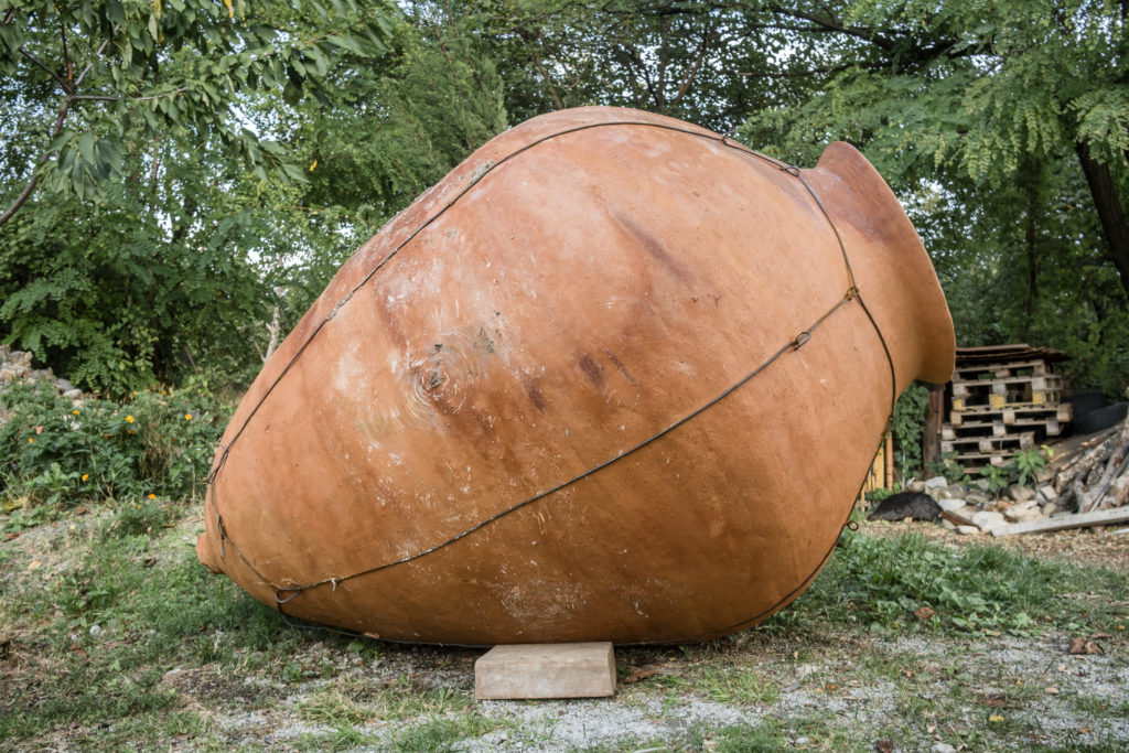 Used in Jaya Travel & Tours article blog "The Philippine Wine Scene" this shows a big kvevri in a garden in front of a stone wall.