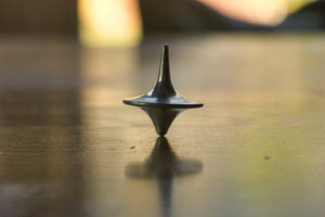 a metal spinner, like the one from the movie inception, spins on a wooden table symbolizing a dream.