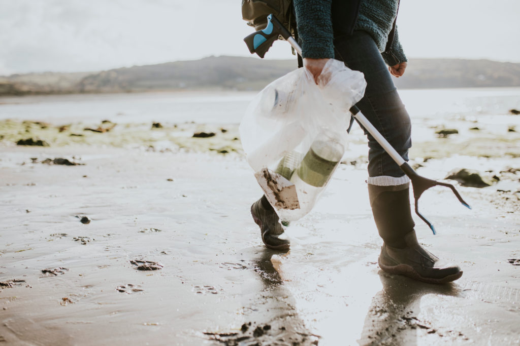 Humanitarian volunteers at beach clean up carrying a garbage bag and grabber on a volunteer trip abroad.