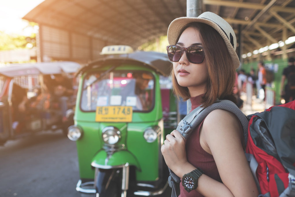 A young female Jaya Travel & Tours customer waits for their shuttle transportation to their hostel at after a flight at the airport in Bangkok, Thailand.
