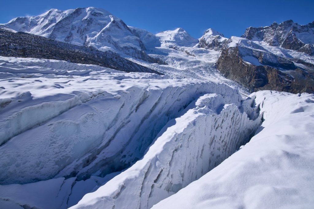 In this image, a giant glacier sits at the bottom of a snowy white mountain and drives up from the ground, ready for tourists to explore. This image is featured in the Jaya Travel & Tours blog, "Which Glacier Should You Visit Quiz," which is a personality travel quiz that determine your next glacier tour.