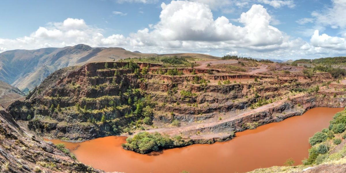 Featured in "Tour Film Locations of Blood Diamond" by Jaya Travel & Tours, this image shows the red terraced ground and a muddy river in South Africa.