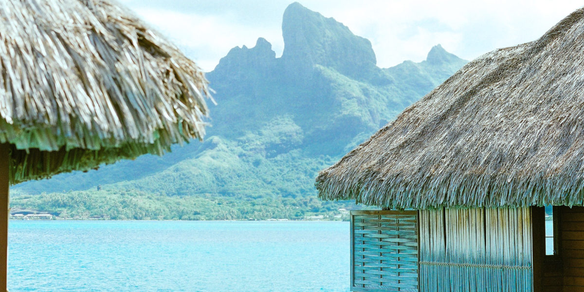 Luxury overwater bungalow hotels at Tahiti resort in Bora Bora, French Polynesia travel with the beach and mountains in the background.