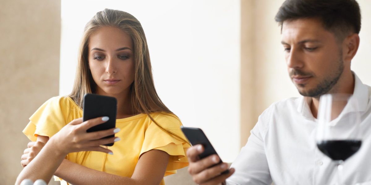 a couple sits at the dinner table playing on their phones and being rude and not performing social etiquette on travel with Jaya.