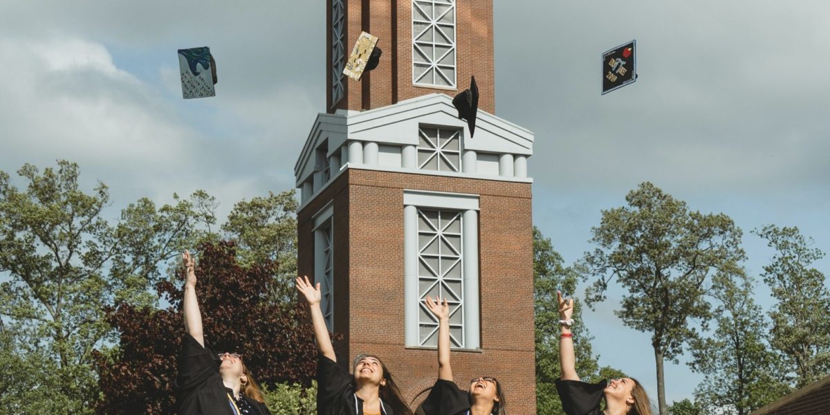 University students tossing up their caps and looking at the sky after graduating from their college study abroad trip tour program.