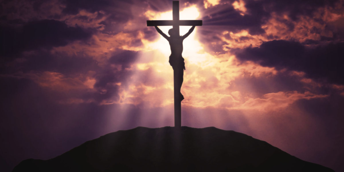 jesus christ superstar is crucified on a cross behind a beautiful purple sunset for Jaya Travel and Tours on location blog.